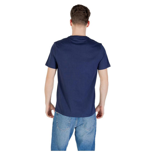 Back view of a man wearing a Lyle & Scott blue cotton T-shirt paired with jeans, showcasing the shirt's simplicity and modern design.